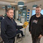 Mieshenkilö esittelee saamaansa kiertopalkintoa